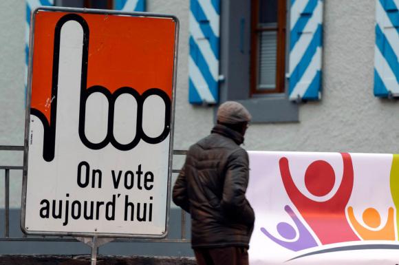 man walks in front of a sign saying on vote