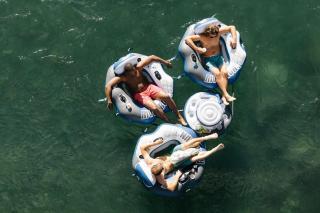 Tre persone galleggiano nel fiume su piccoli gommoni