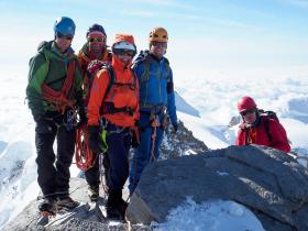 Author stands with other climbers on summit, posing for picture