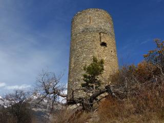 Blick von unten auf alten, runden Steinturm vor blauem Himmel