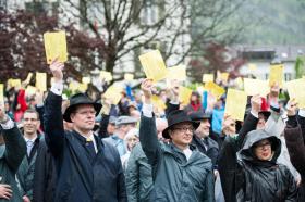 People hold ballot papers in the air during an open air vote in the rain