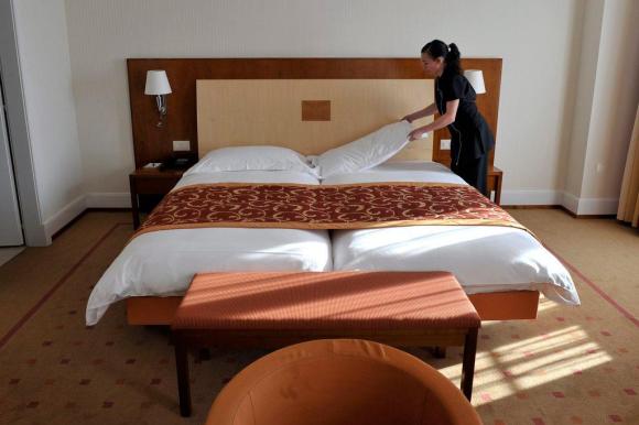 A chambermaid makes a bed in a Swiss hotel.