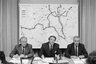 ベルンでアルプス縦断鉄道計画を発表するアドルフ・オギ運輸大臣（当時、中央）とフリッツ・ビュルキ連邦交通局局長（当時）