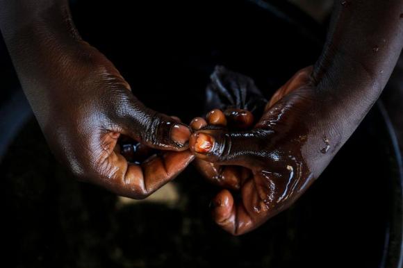 A pair of hands, coated in liquid, work with gold