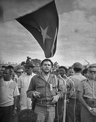 El Che en su aspecto característico, uniforme verde olivo, pistola y puro.