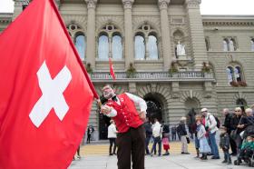 Homem com uma bandeira suíça frente ao Palácio Federal em Berna