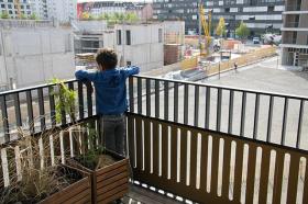 Un niño se asoma al balcon y observa las obras que tiene enfrente