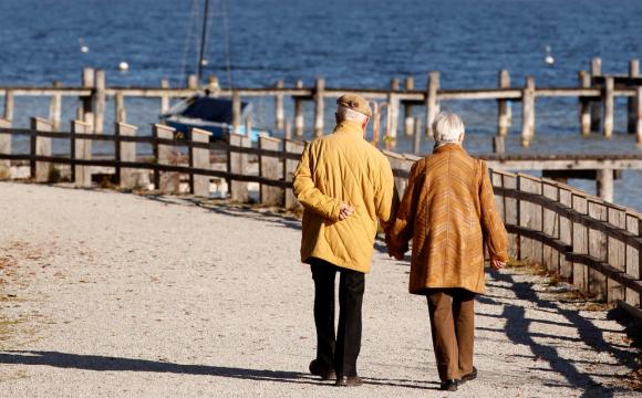 Una pareja de personas mayores camina en una playa.