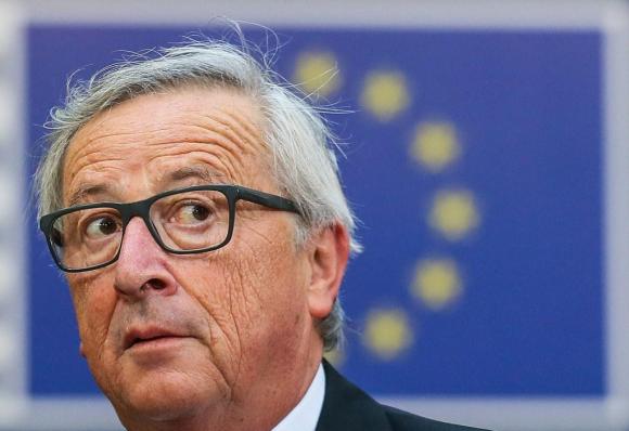 Grossaufnahme des Kopfes von Juncker mit Brille, im Hintergrund eine EU-Fahne.