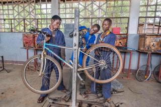 Tres jóvenes reparan una bicicleta