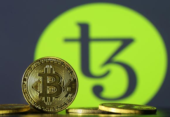 A bitcoin stands in front of the Tezos logo