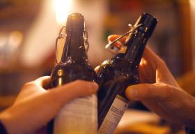 Dos manos, dos botellas de cerveza y un brindis