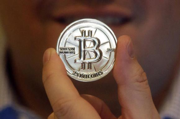 A man s hand holding a 25 Bitcoin token
