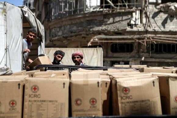 Workers empty the convoys of humanitarian aid in Douma, Syria