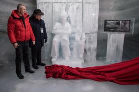 Zwei Männer stehen neben einer Eis-Skulptur, am Boden liegt ein rotes Tuch.