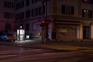 Une cabine téléphonique illumine une rue pendant la nuit.
