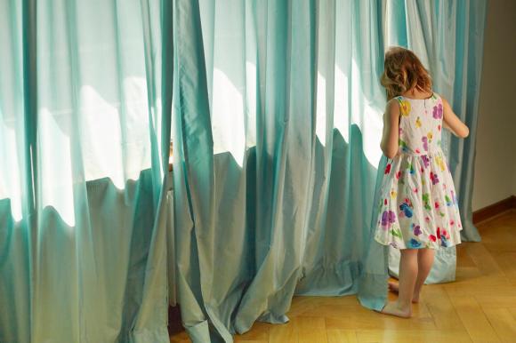Girl hiding behind a curtain