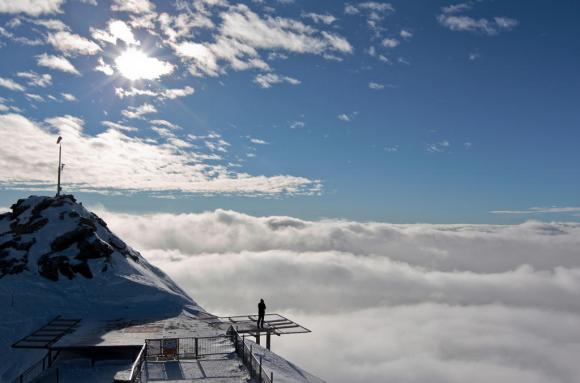 Ein Touristen geniesst die Aussicht von der luftigen Heli-Landeplattform bei der Bergstation Corvatsch