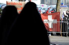 スイスのイスラム中央委員会年次総会開催に反対するデモを見つめるブルカ姿の女性２人