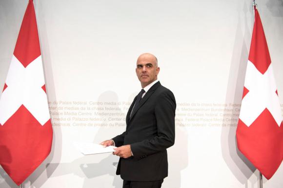 Swiss President Alain Berset stands between two Swiss flags