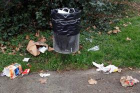 Garbage lies on the ground around a Geneva waste bin