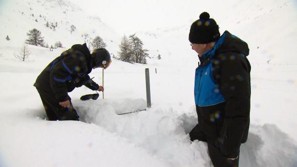 Two men measuring the height of snow