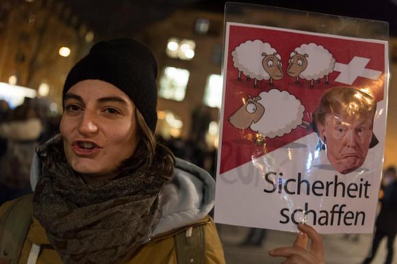 Demonstrator with poster of sheep kicking Donald Trump out of Switzerland.