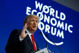 世界経済フォーラムのロゴを背景に演説するトランプ米大統領
