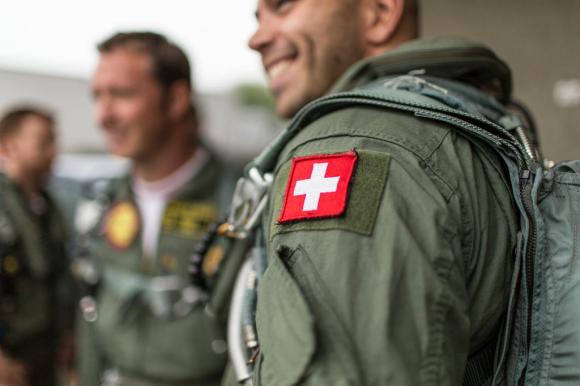 A Swiss cross is displayed on the upper arm of the uniform of a Patrouille Suisse member.
