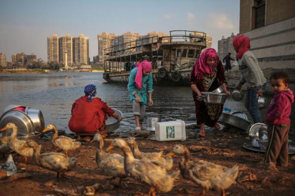 Women wash dishes using water from the Nile River in Cairo, Egypt