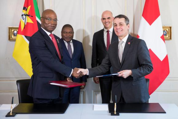 Quatro homens, políticos da Suíça e Moçambique, ao assinar acordo