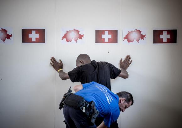 Ein Polizist untersucht einen schwarzen Mann, der seine Hände an die Mauer legen muss.