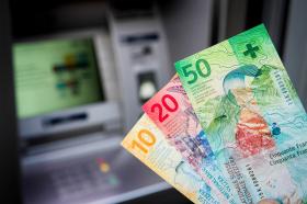 Swiss franc bank notes and a cash machine