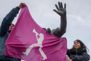 امرأة ترفع راية بنفسجية خلال مظاهرة احتجاجية