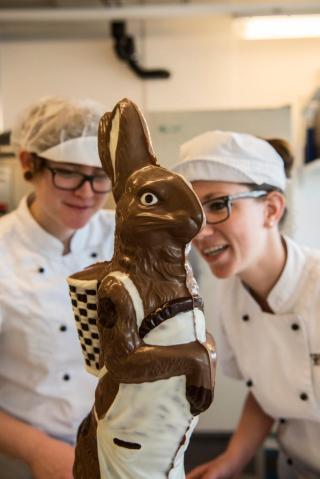 Dos confiteras contempla el conejo de chocolate terminado.