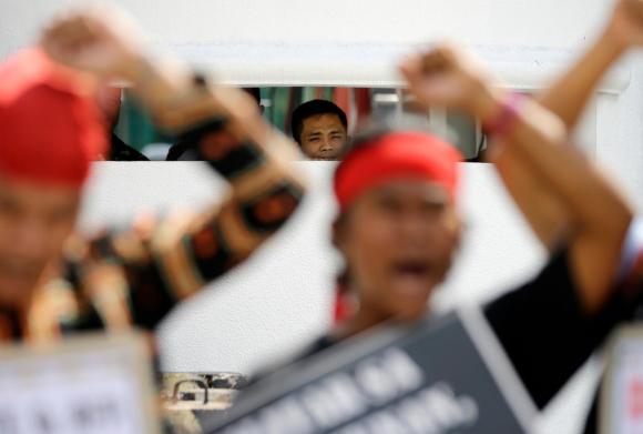 A military guard watches as Filipino indigenous people raise their clenched fists during a rally