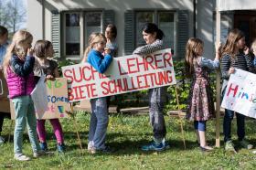 Kinder halten ein Transparente mit der Aufschrift: suche Lehrer, biete Schulleitung