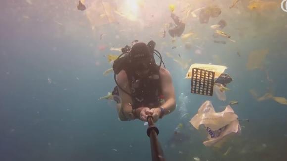 Diver swimming among plastic and other waste