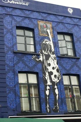 Fachada con la pintura de una niña en Portobello Road, en Londres