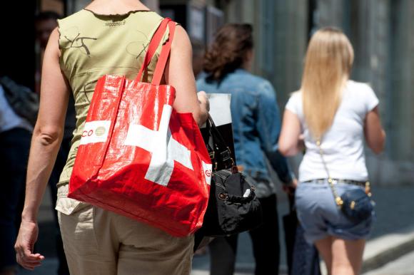 Mujer lleva una bolsa roja con la cruz blanca