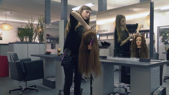 Hair dresser apprentice works on a wig