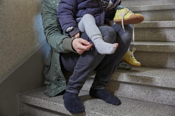 Mulher sentada numa escadaria com criança de meias furadas