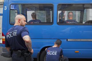 Due agenti in prossimità di un furgone blu della polizia, visto parzialmente; agenti all interno