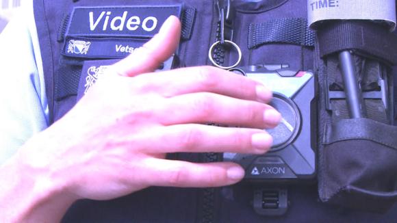police officer touches camera to turn it on