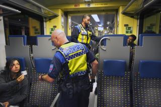 Interno di un treno; un agente chiede i documenti a una passaggera, che mostra la carta d identità