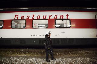 Poliziotto solo, in piedi accanto a un vagone ristorante, come a controllare il lato del treno