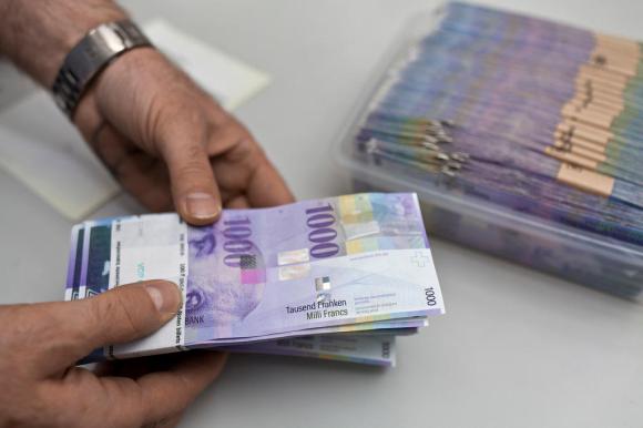 Two hands holding a bundle of CHF1,000 bank notes
