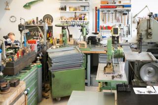 A room full of tools and machinery - a man sits behind a counter in the left corner.