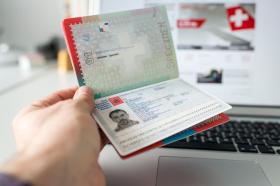 A Swiss biometric passport is held open to the ID photo page