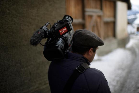 Journalist carrying TV camera walks through snow